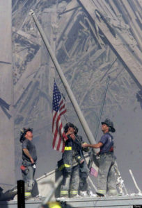 NEW YORK - SEPTEMBER 11: (EDITORIAL USE ONLY - NO COMMERCIAL SALES) Firefighters raise a U.S. flag at the site of the World Trade Center after two hijacked commercial airliners were flown into the buildings September 11, 2001 in New York.  (Photo by 2001 The Record (Bergen Co. NJ)/Getty Images)